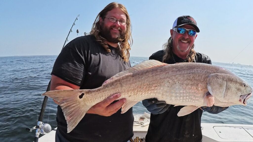 two men holding a redfish after october fishing